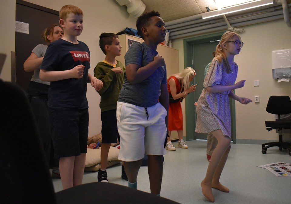 Fem barn danser i et klasserom. 