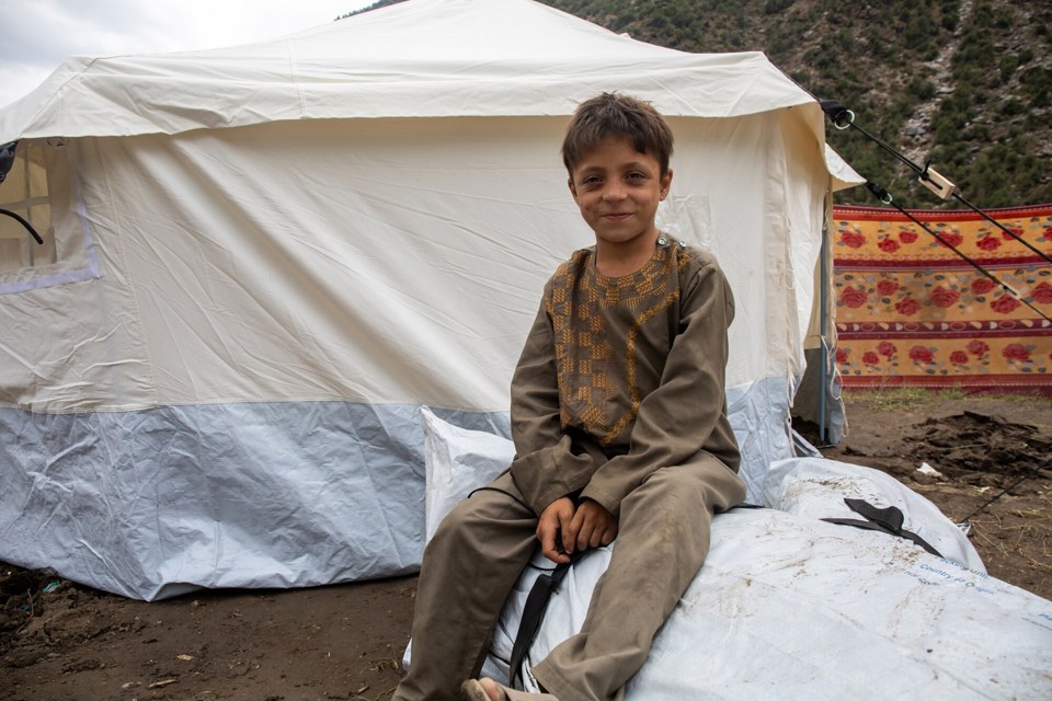 En gutt sitter foran et hvitt telt.