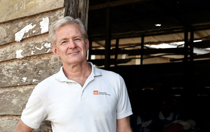 Jan Egeland står i hvit skjorte ved en slitt døråpning.