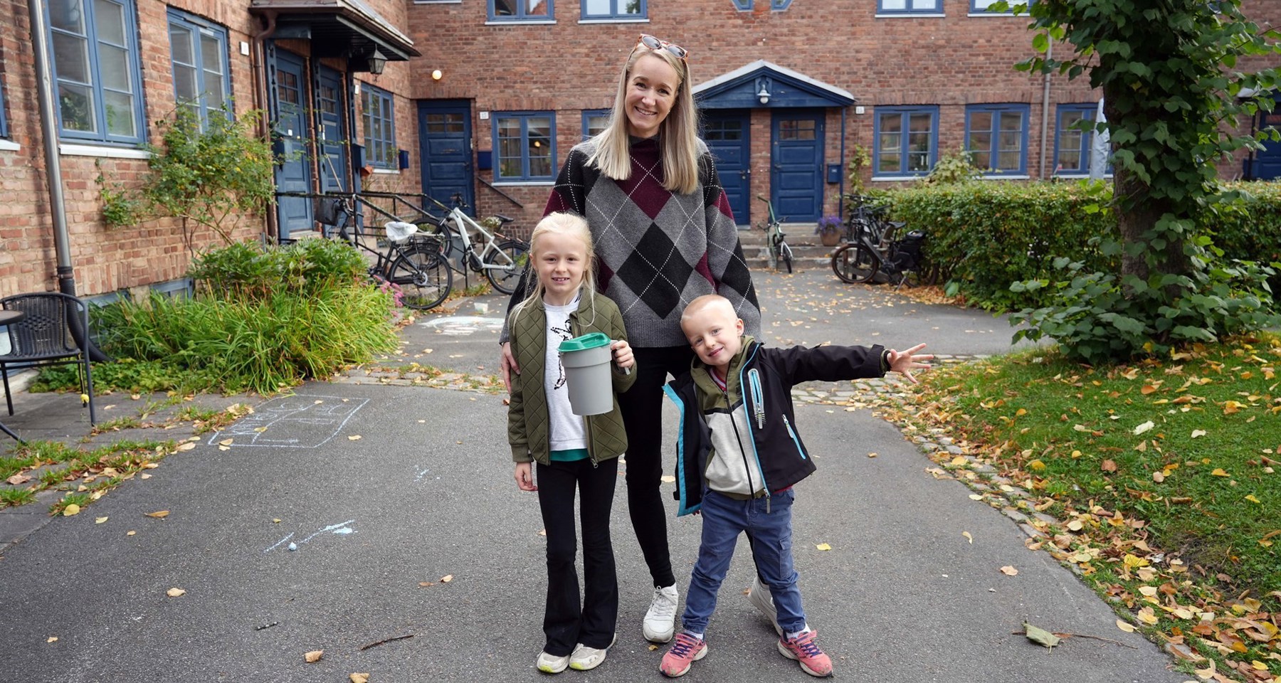 En mor og to barn står med bøsse i et nabolag.