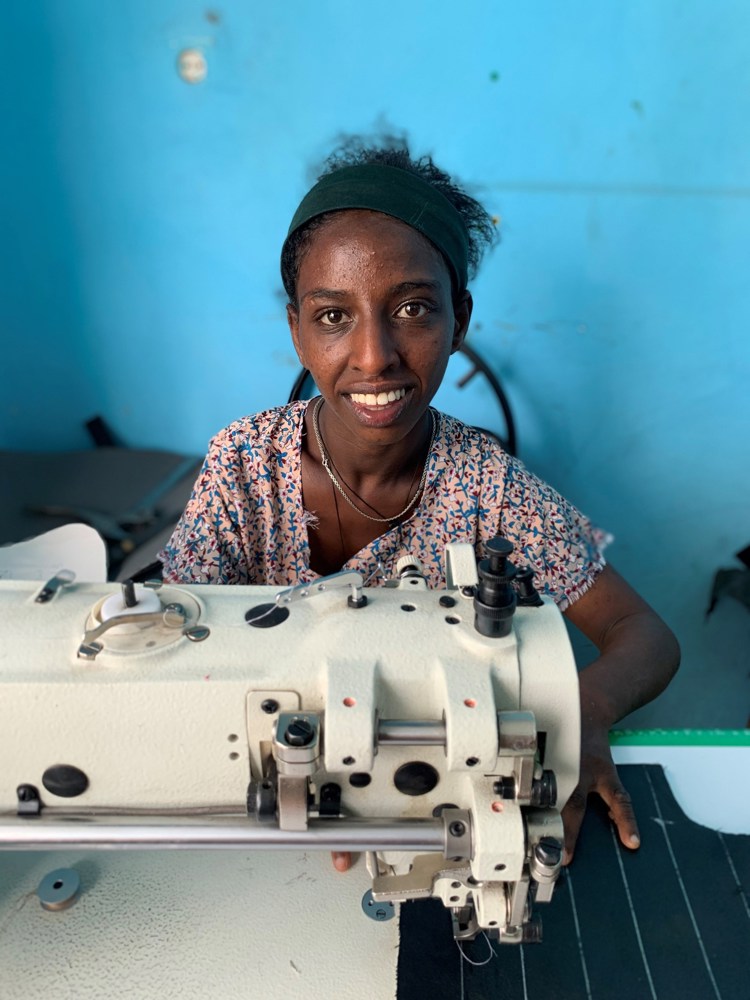 En jente sitter ved symaskin i Etiopia.