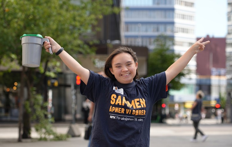 Smilende jente holder hendene i været og har en bøsse i den ene hånda.