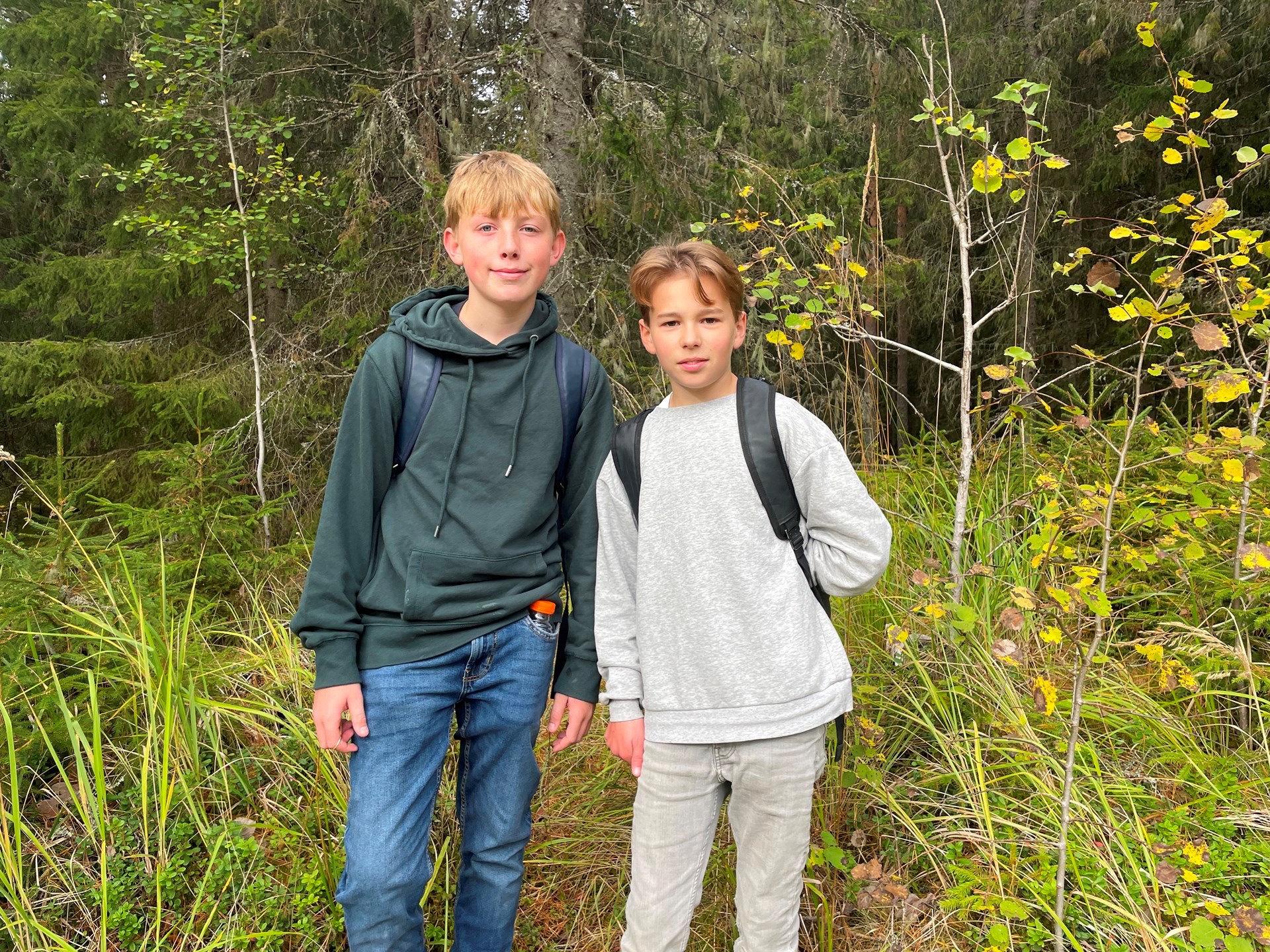 To gutter med sekker står i en skog
