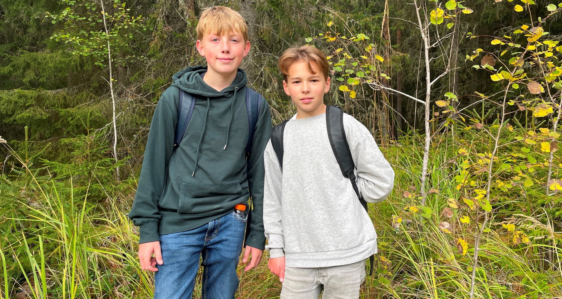 To gutter med sekker står i en skog
